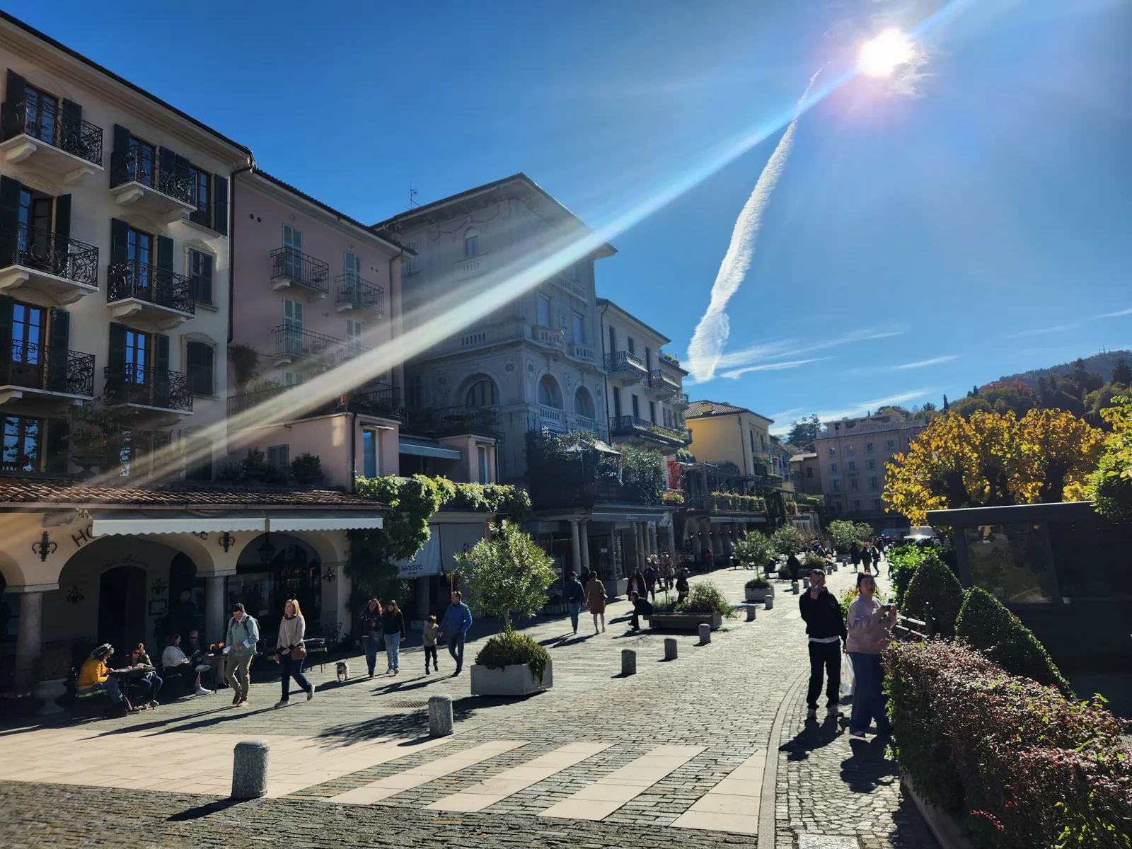A cobblestone village piazza with cafe umbrellas on Lake Como