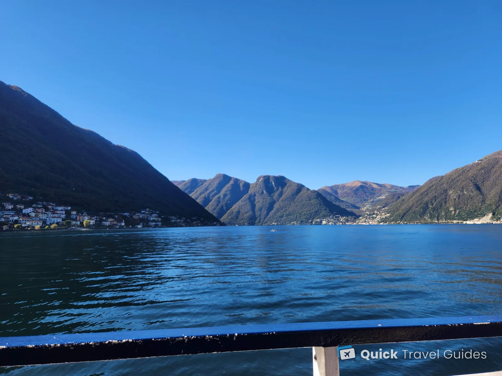 View from a Lake Como ferry deck across the water to steep wooded mountains