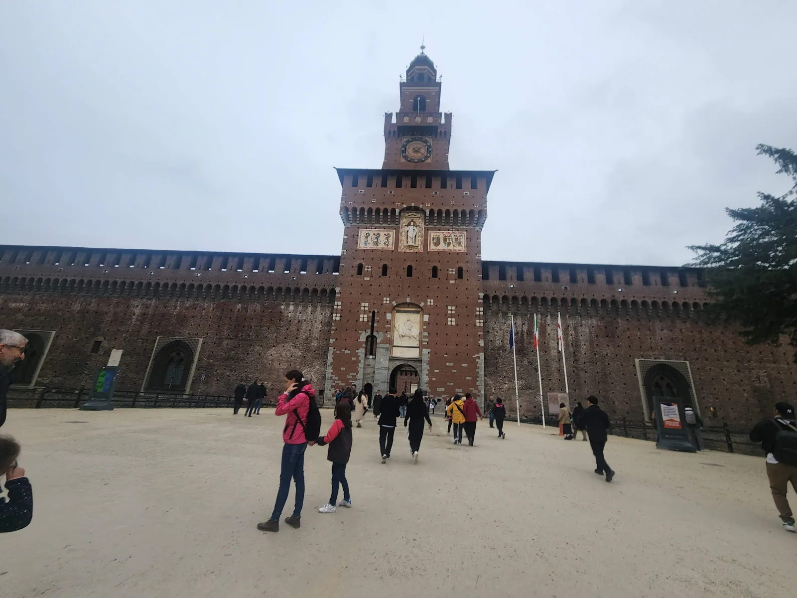 The Castello Sforzesco with its fountain and people walking in Milan