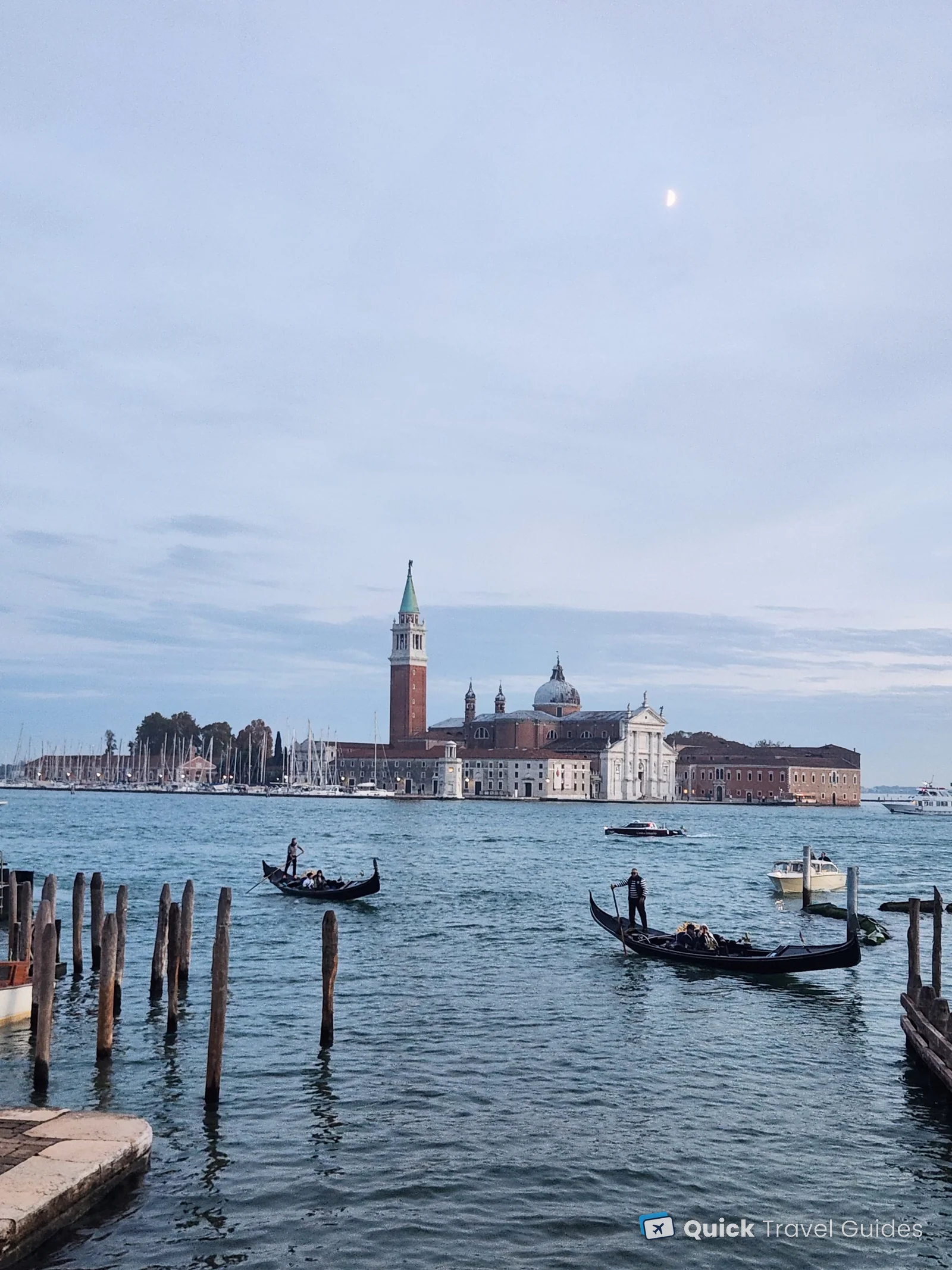Gondolas crossing the basin in front of San Giorgio Maggiore at dusk, with the moon above, Venice