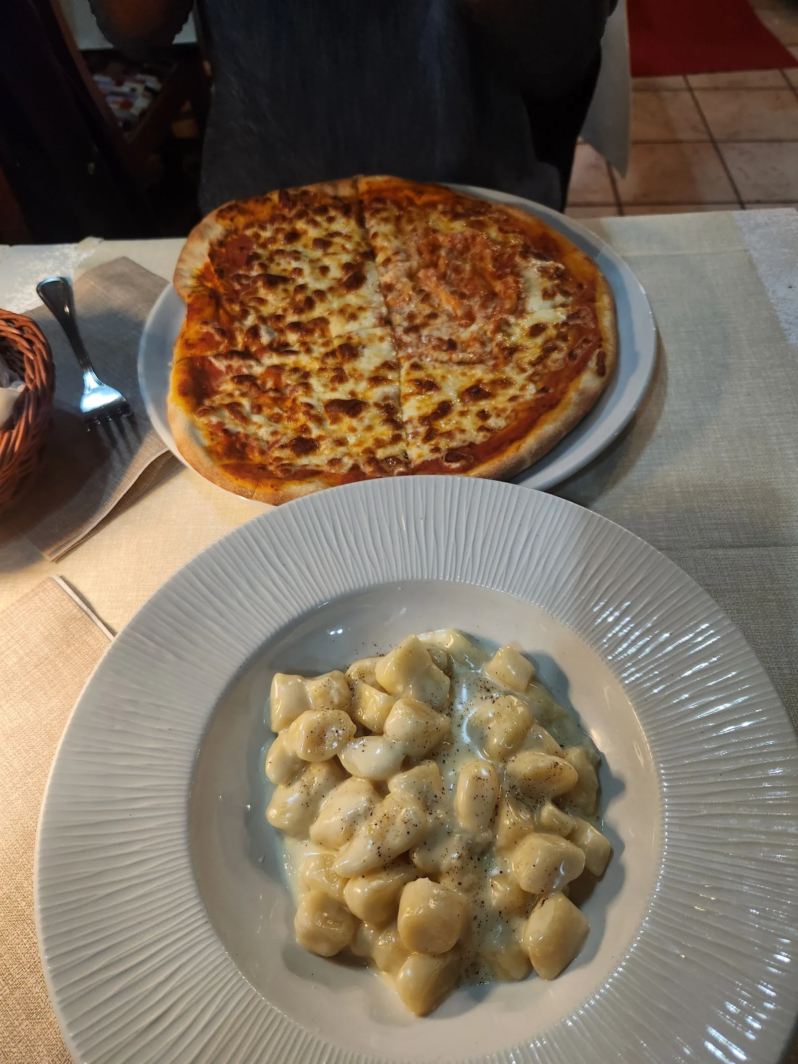A pizza and a plate of gnocchi on a table in Venice