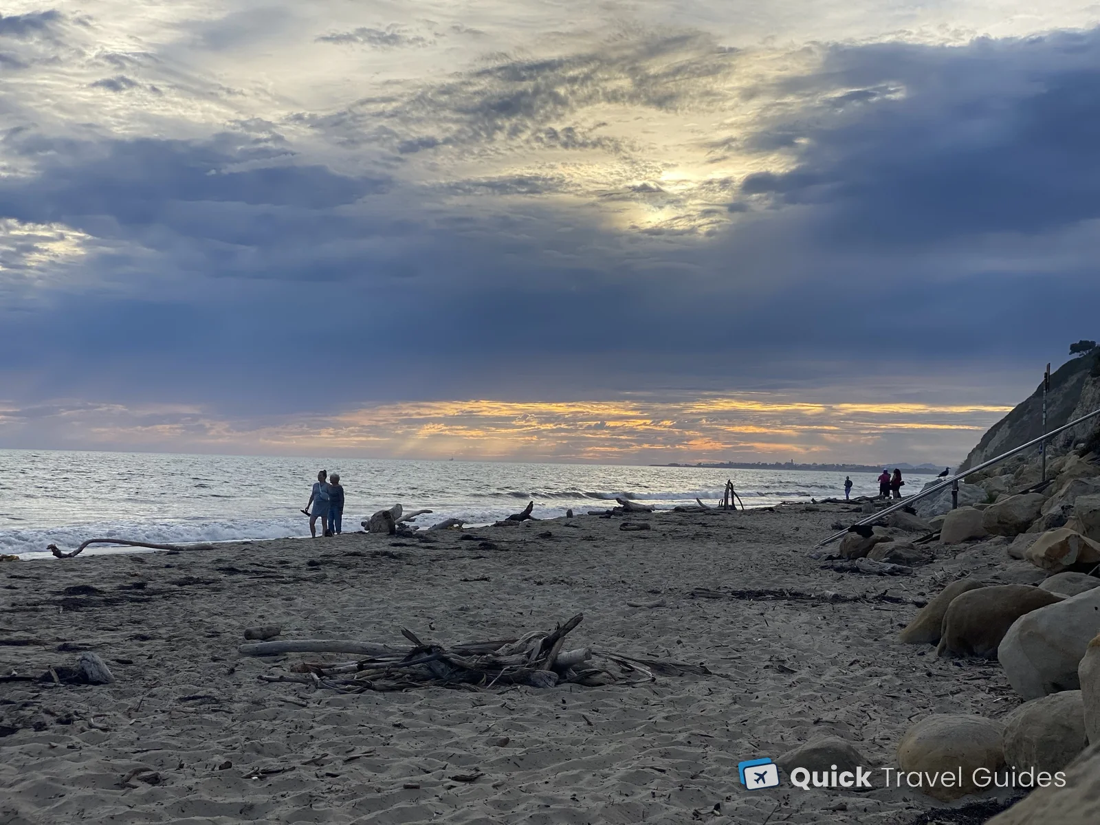 Sunset at Hendry's Beach (Arroyo Burro Beach) in Santa Barbara, near The Boathouse, with driftwood on the sand and cliffs on the right
